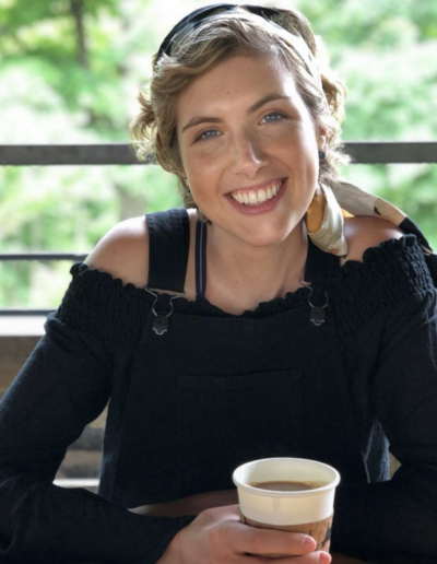 Photo of young woman smiling while sitting holding a cup of coffee